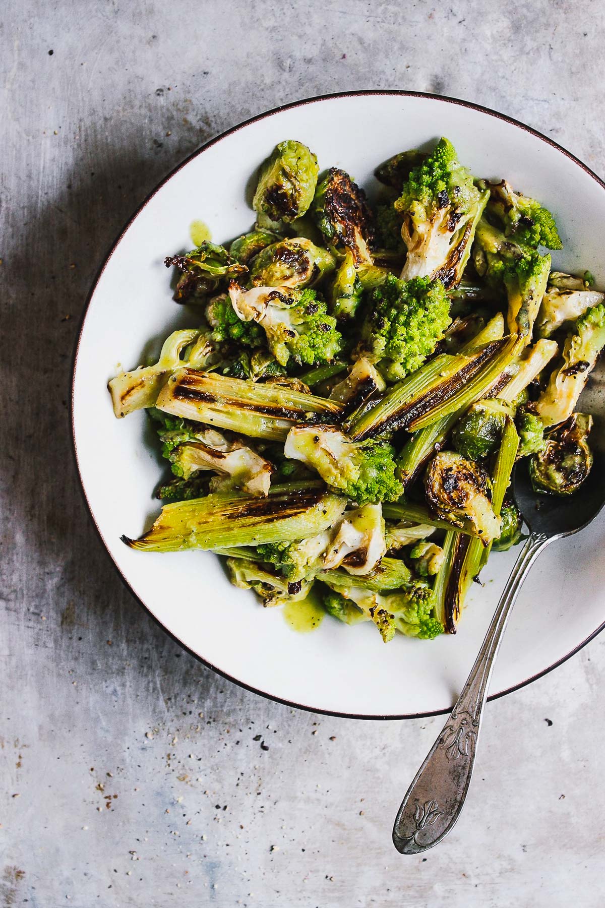 A charred, roasted romanesco salad with brussels and leeks, and tossed in a salty green olive dressing. A warm and hearty salad perfect for fall or winter. #roastedromanesco #romanescorecipes #romanescosalad