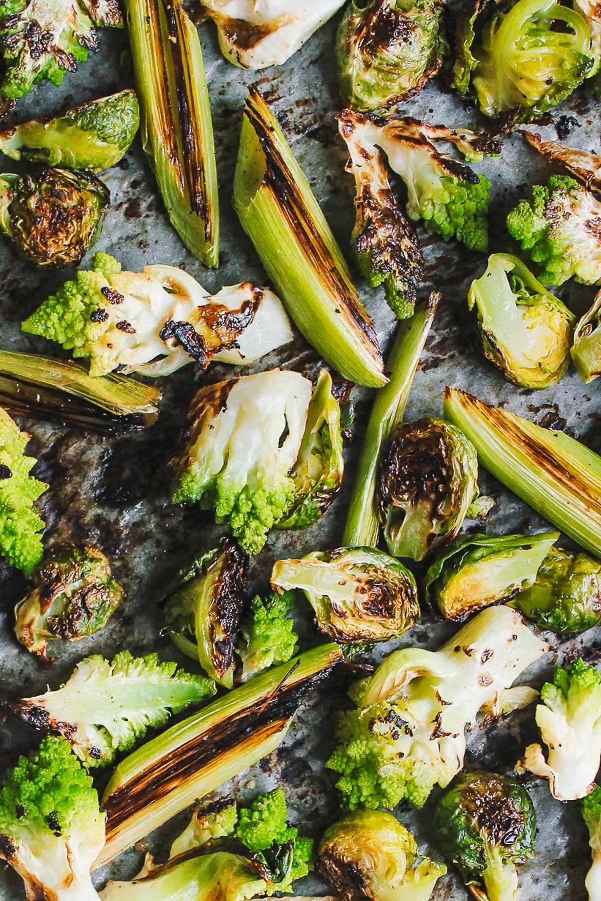 A charred, roasted romanesco salad with brussels and leeks, and tossed in a salty green olive dressing. A warm and hearty salad perfect for fall or winter. #roastedromanesco #romanescorecipes #romanescosalad