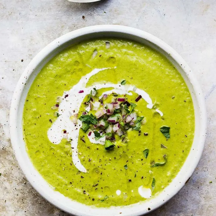 a bowl of broccoli and bean soup with a spoon