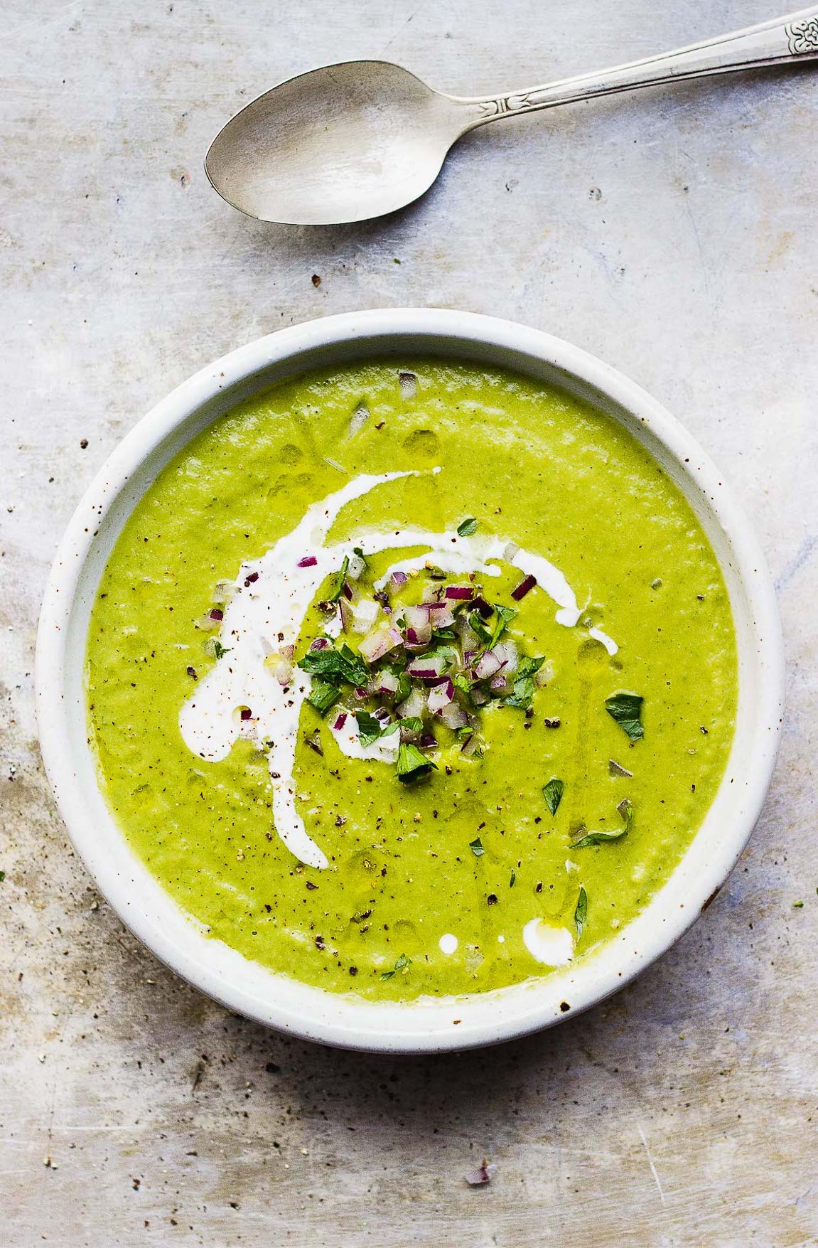 a bowl of broccoli and bean soup with a spoon