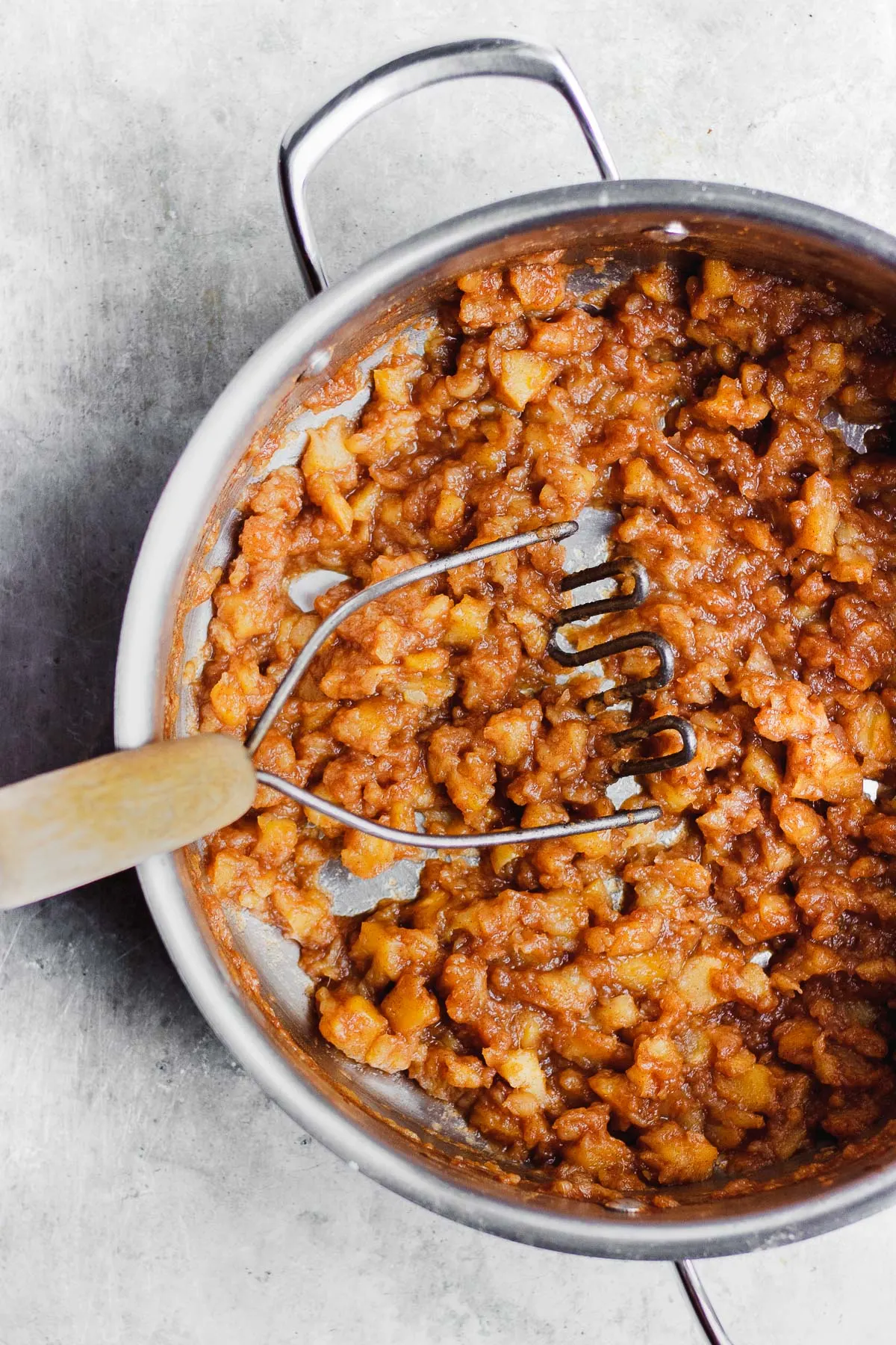 stovetop apple sauce with masher in pot