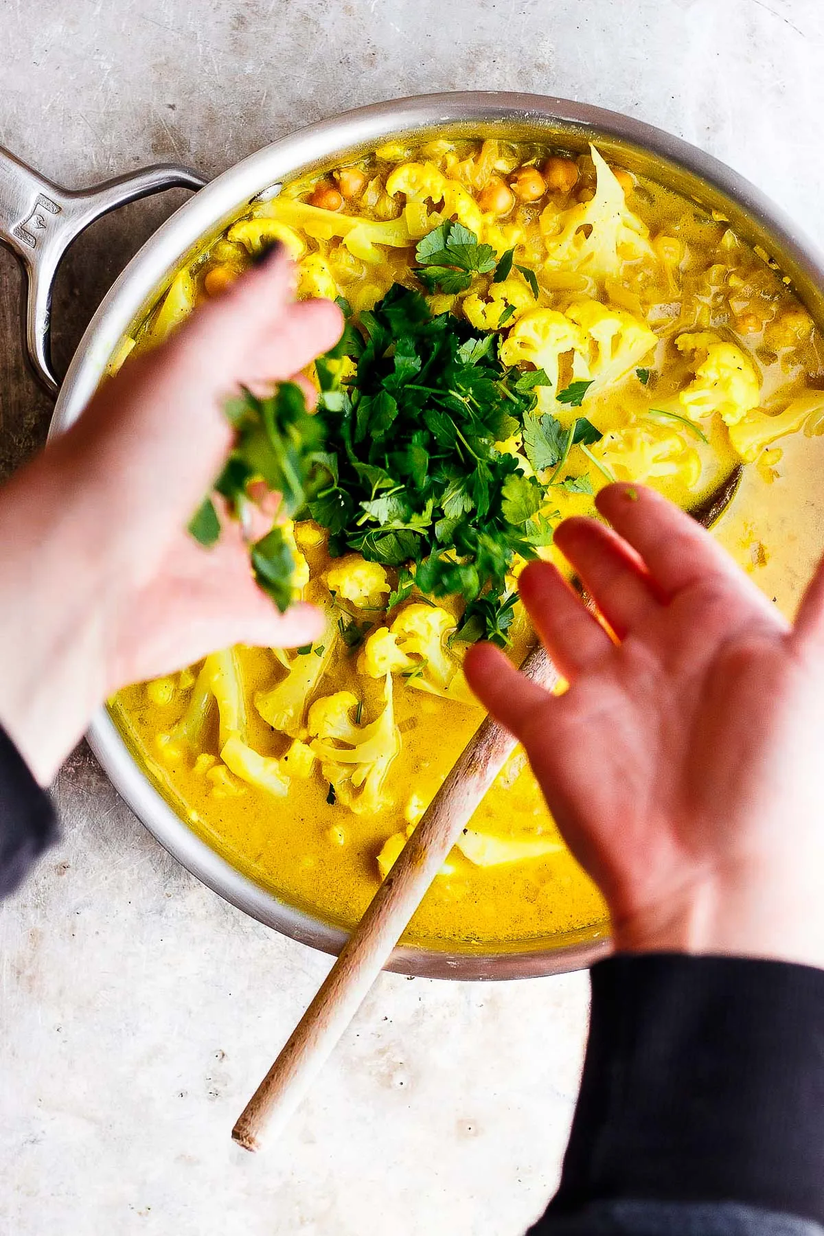 hands throwing parsley into stew