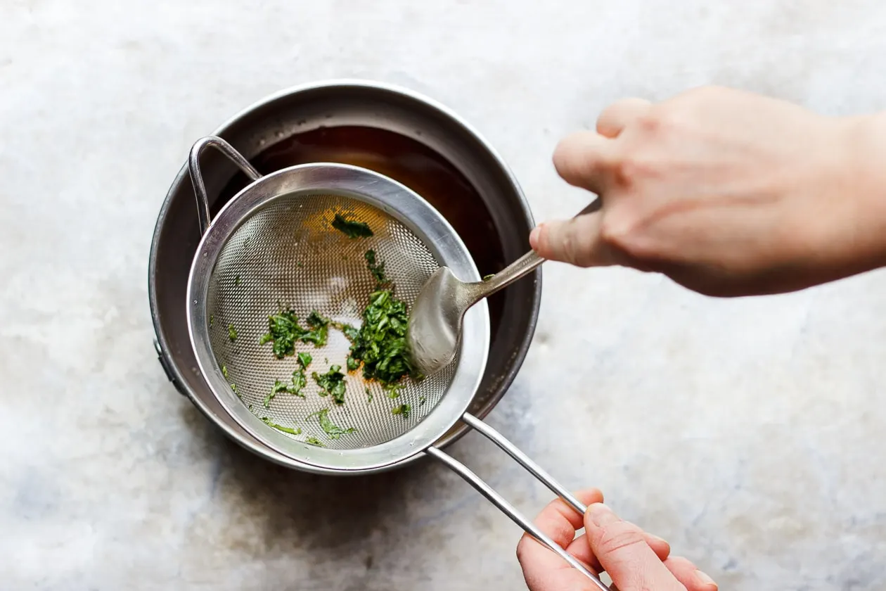 fresh mint simple syrup in a sieve