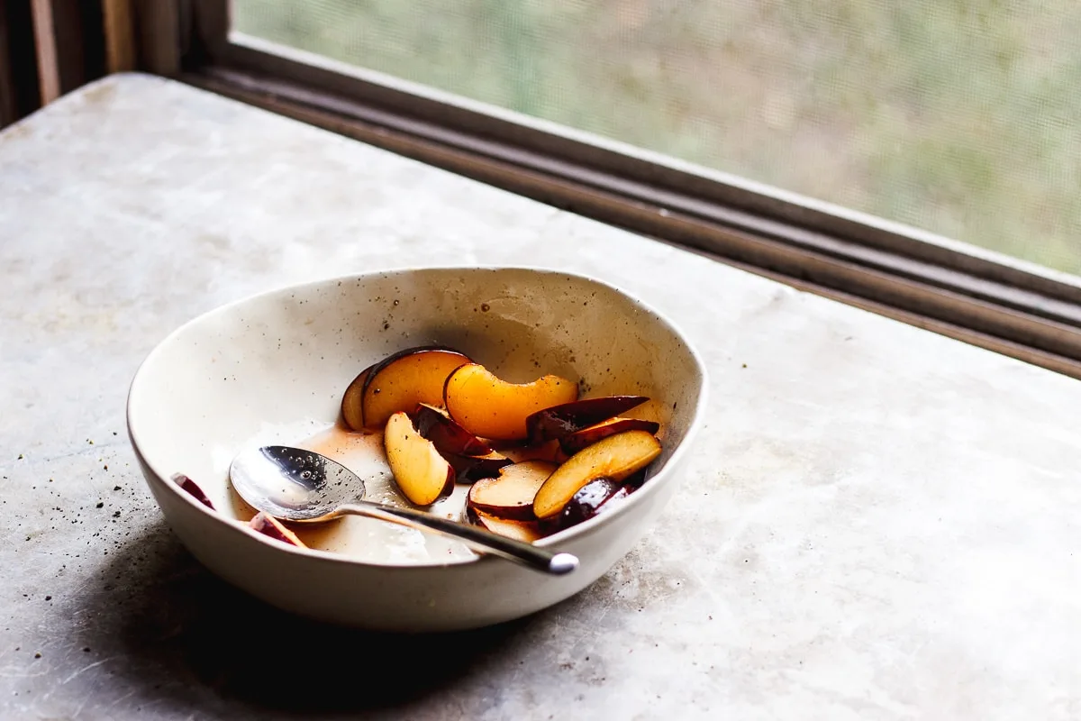 plums sliced in a bowl on a windowsill