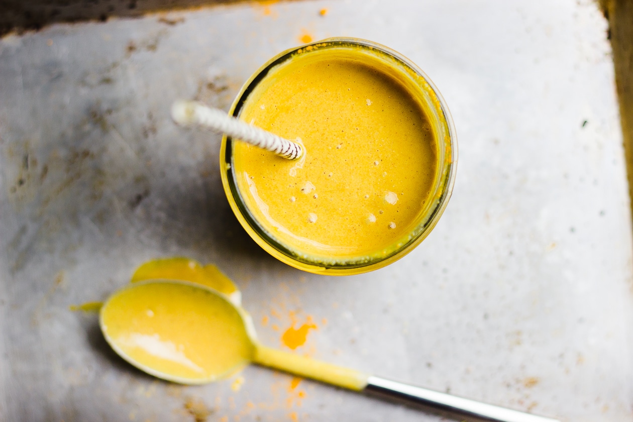 golden yellow smoothie with a straw