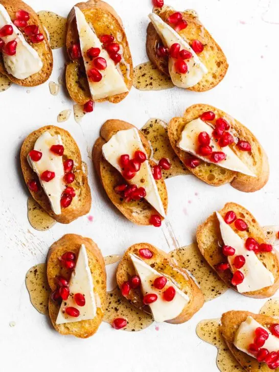 A brie crostini topped with black pepper honey and pomegranate. An easy, beautiful, simple, festive holiday brie appetizer.