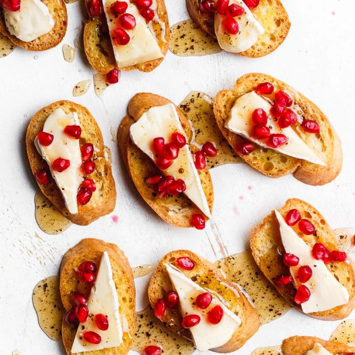 A brie crostini topped with black pepper honey and pomegranate. An easy, beautiful, simple, festive holiday brie appetizer.