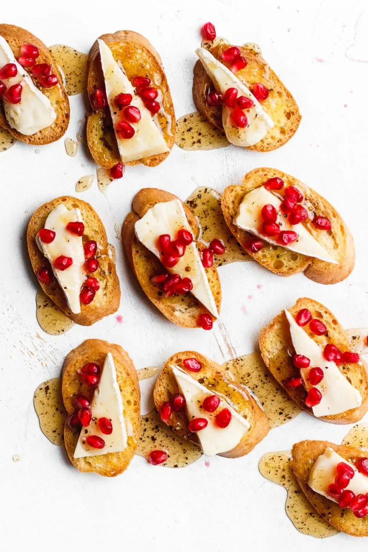 A brie crostini topped with black pepper honey and pomegranate. An easy, beautiful, simple, festive holiday brie appetizer.