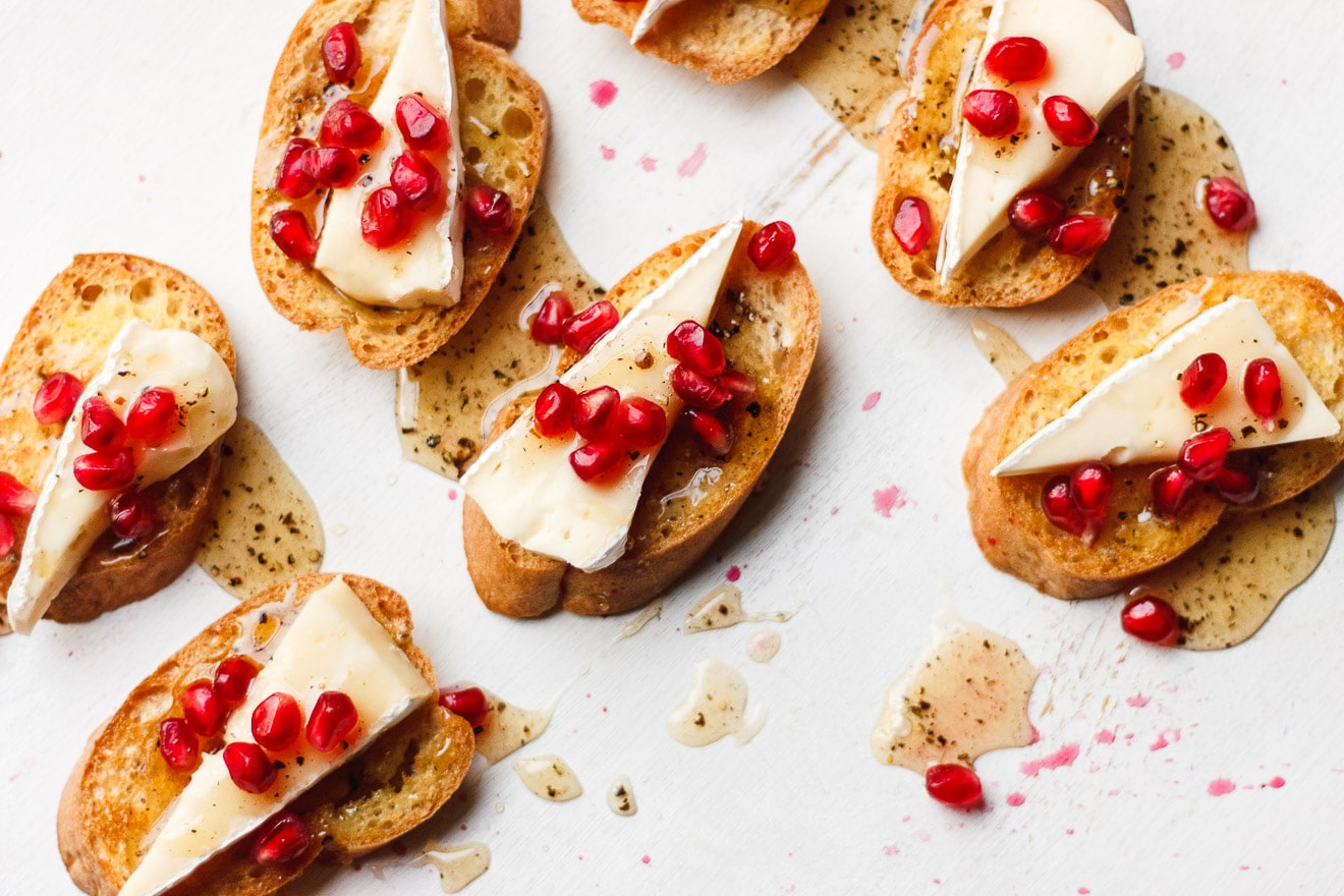brie crostini topped with black pepper honey and pomegranate