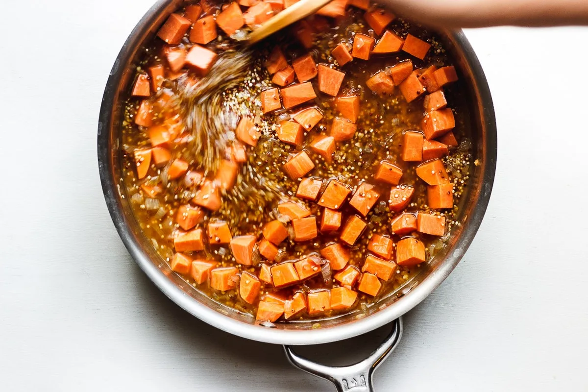 stirring sweet potato and quinoa in a pan