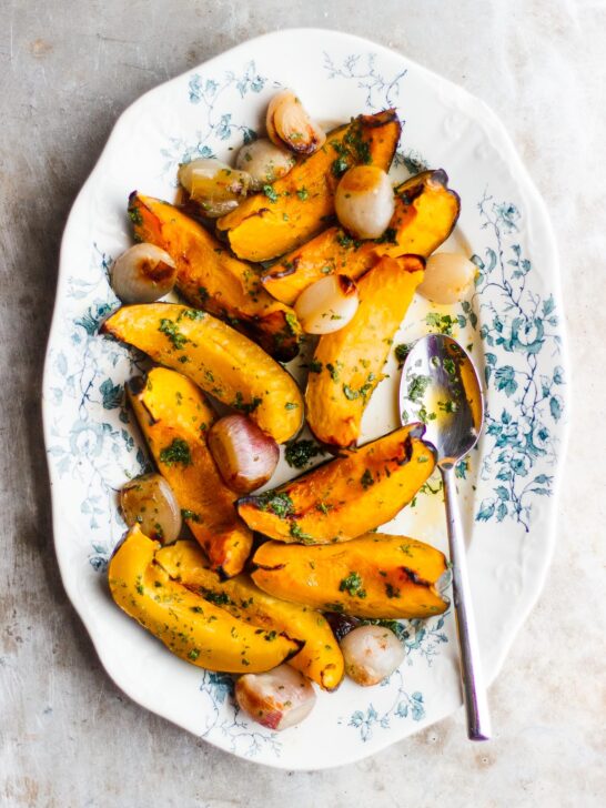 roasted acorn squash and shallots on a plate with a spoon