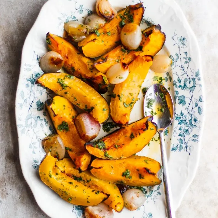 roasted acorn squash and shallots on a plate with a spoon