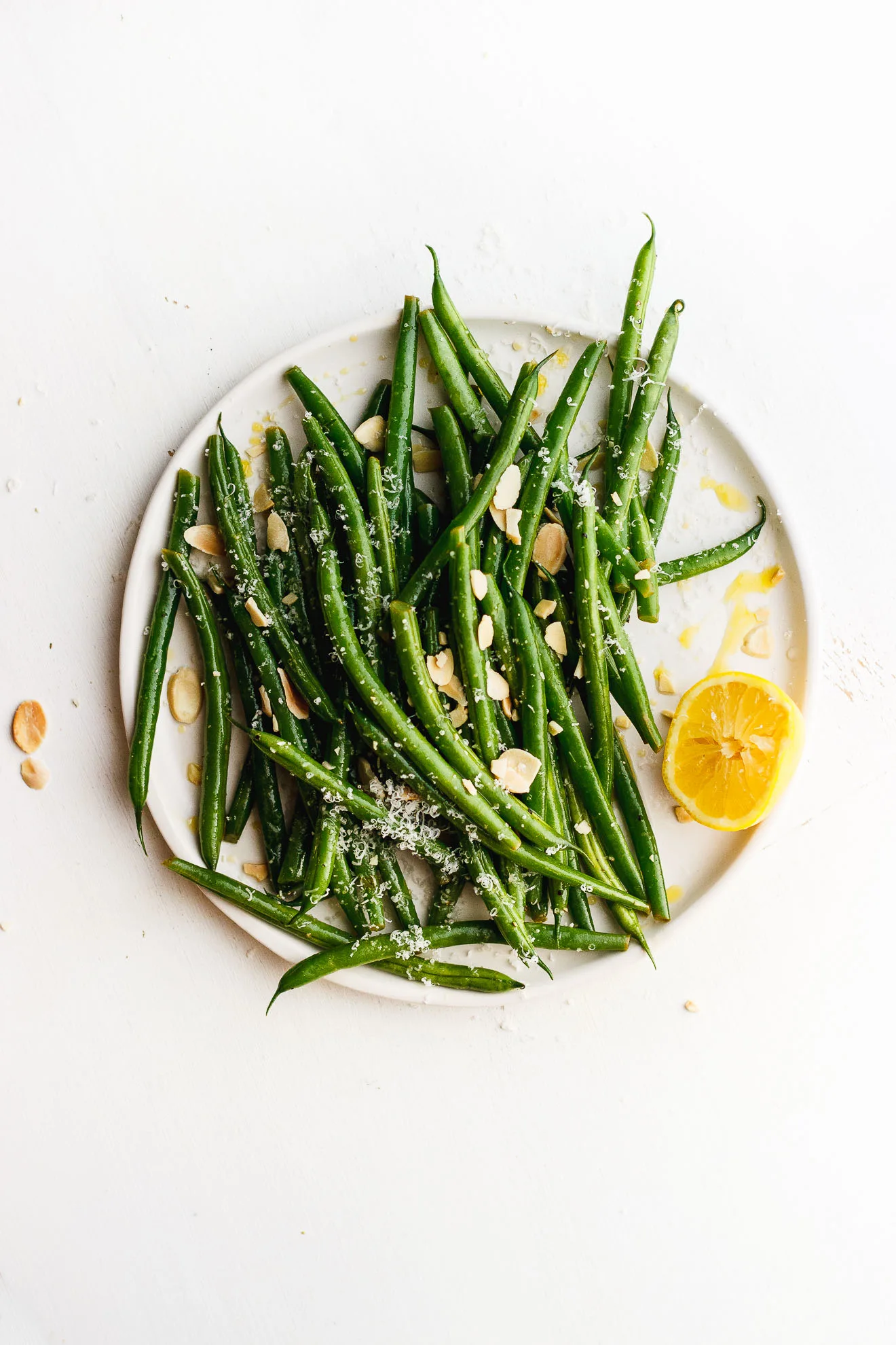 lemony green beans on a plate with toasted almonds and lemon and cheese