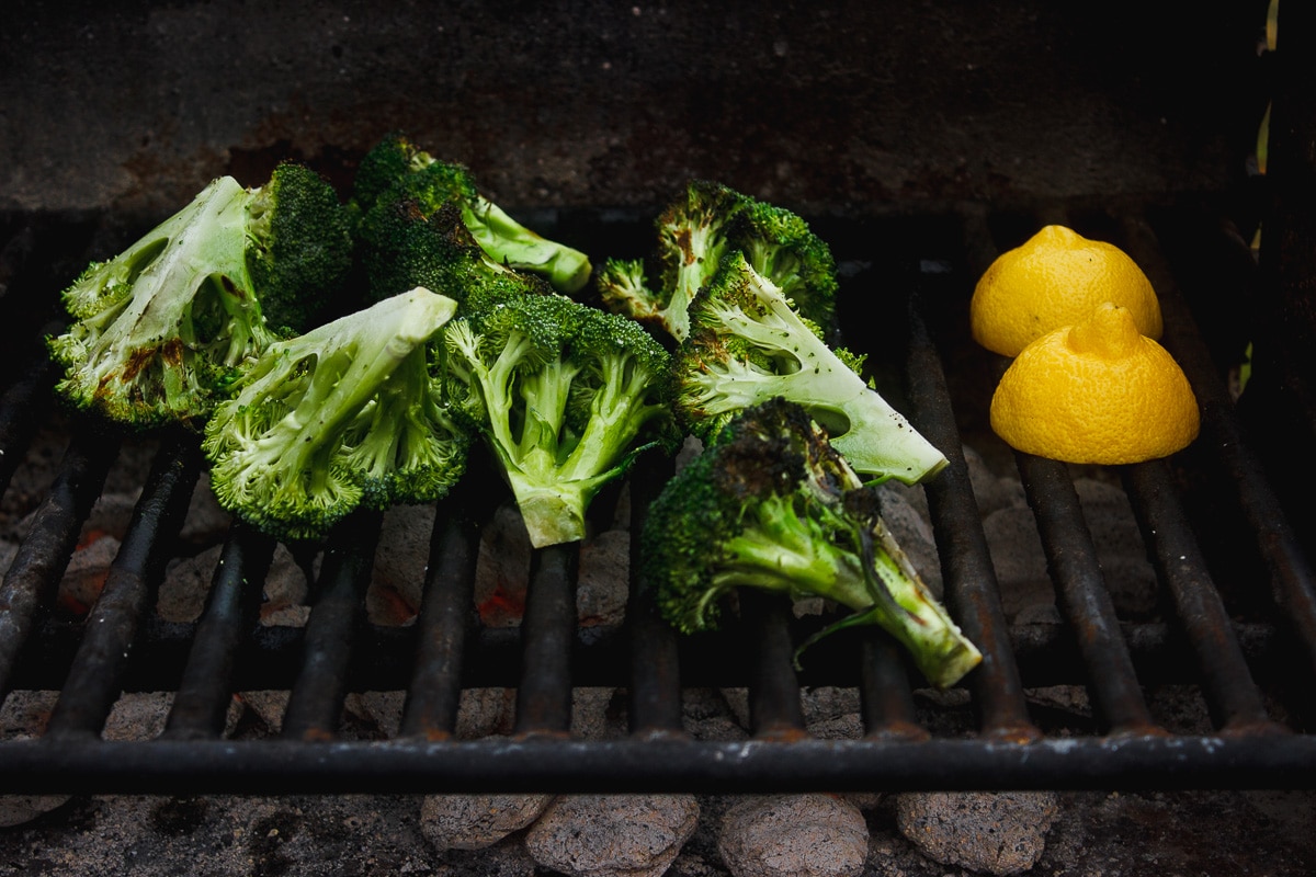 Grilled broccoli that is tossed in a zesty, charred lemon and parsley sauce. A vegan grilled side dish for anytime of year. #grilledbroccoli #grilledlemon #charredbroccoli