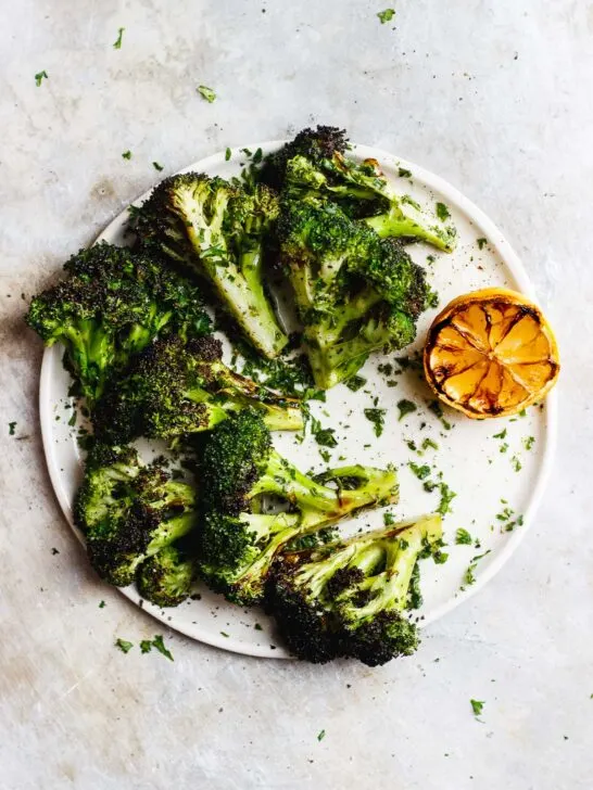 Grilled broccoli that is tossed in a zesty, charred lemon and parsley sauce. A naturally vegan and gluten-free side dish. #grilledbroccoli #grilledlemon #charredbroccoli