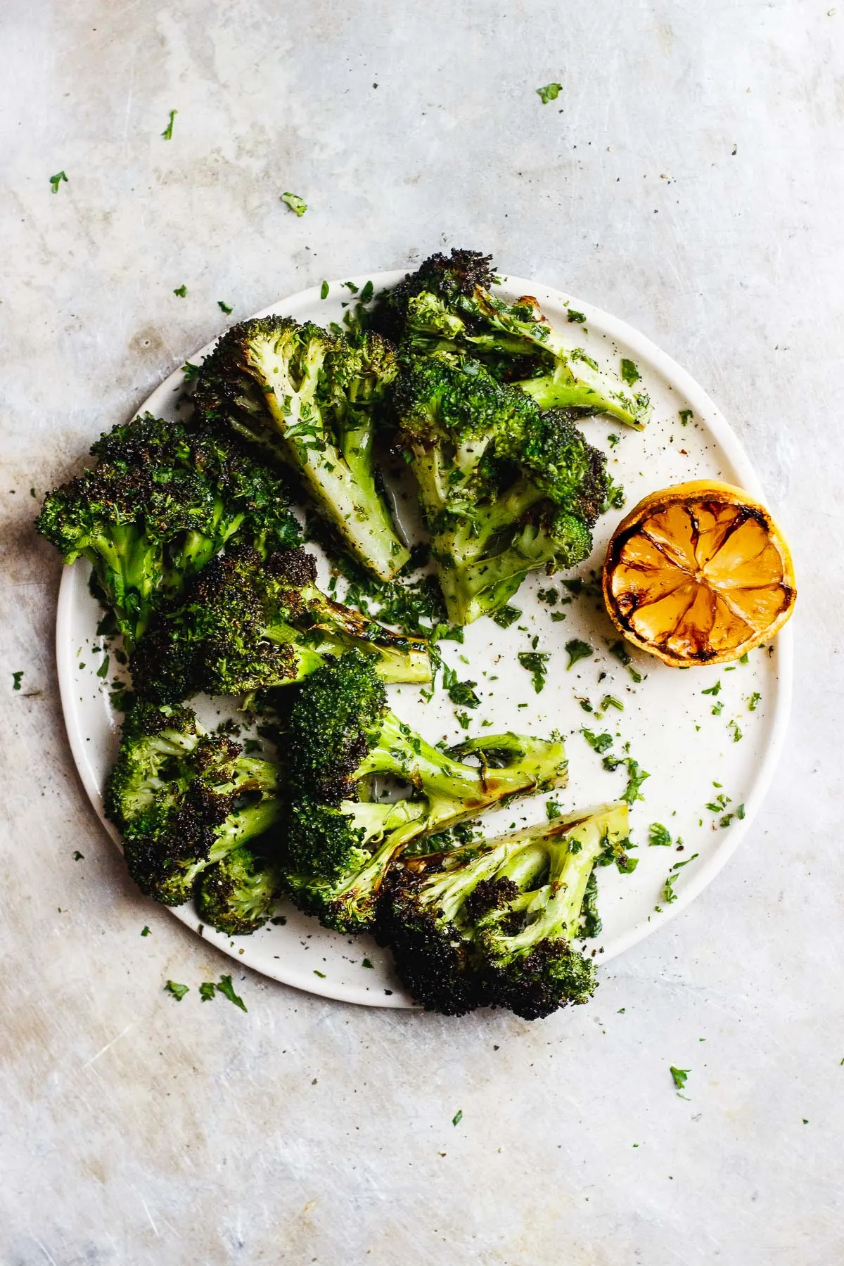 Grilled broccoli that is tossed in a zesty, charred lemon and parsley sauce. A vegan grilled side dish for anytime of year. #grilledbroccoli #grilledlemon #charredbroccoli