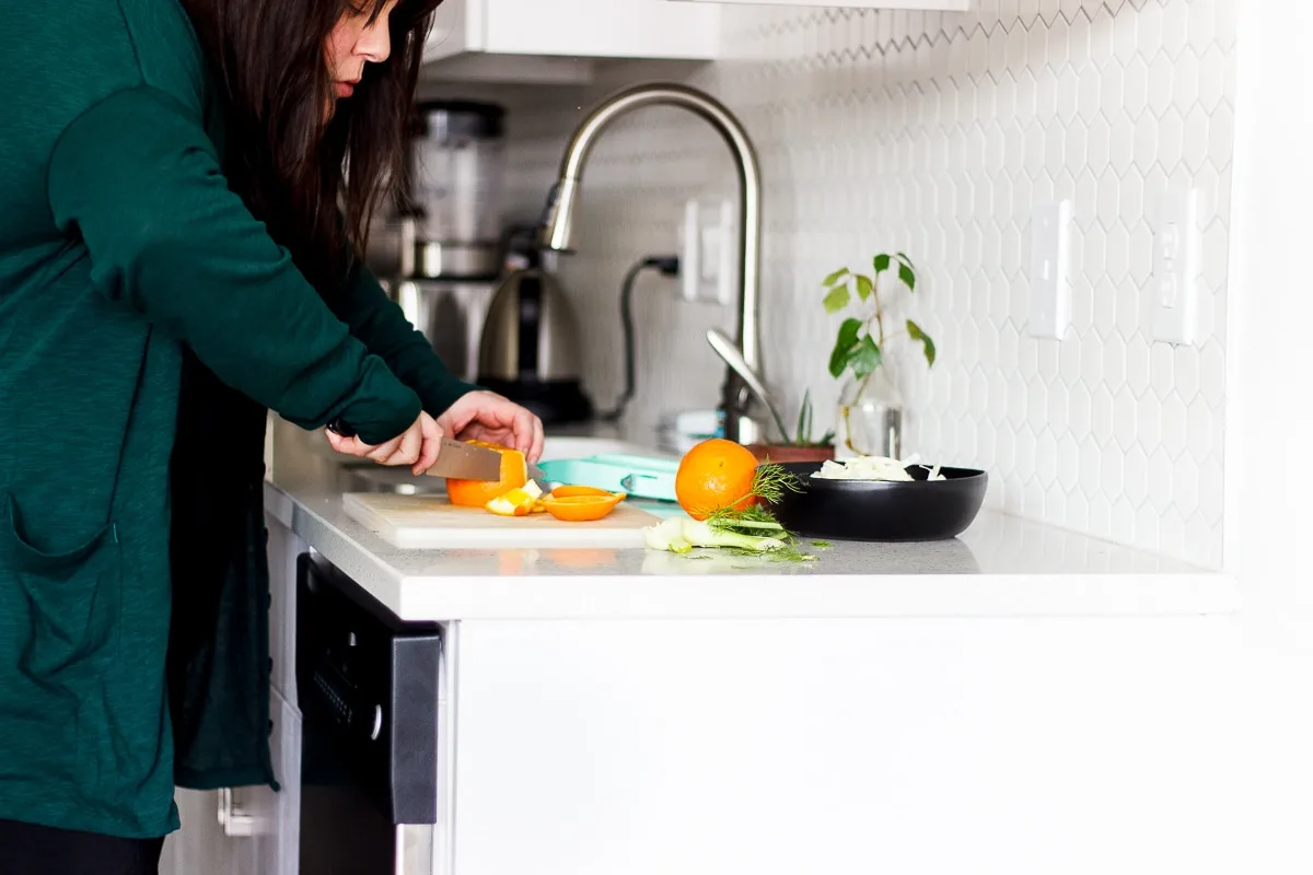 woman cutting an orange in a kitchen