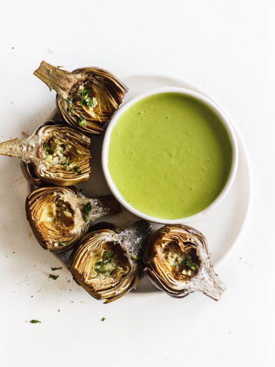roasted artichokes on a plate with green goddess sauce
