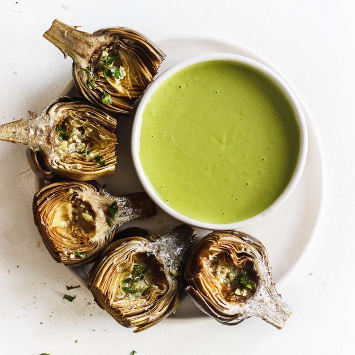 roasted artichokes on a plate with green goddess sauce