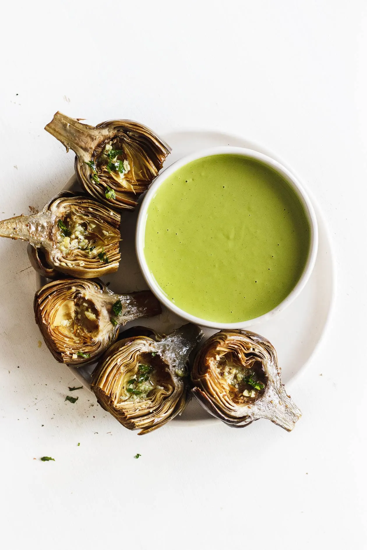 roasted artichokes on a plate with green goddess sauce